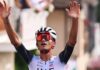 Isaac del Toro raises his hands in the air to celebrate winning a race