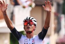 Isaac del Toro raises his hands in the air to celebrate winning a race