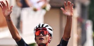 Isaac del Toro raises his hands in the air to celebrate winning a race