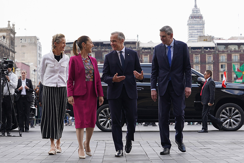 Claudia Sheinbaum and Mark Carney gesture and laugh as the walk into Mexico's National Palace, accompanied by two other officials