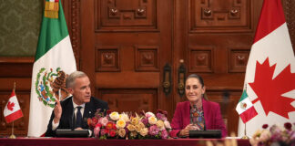 President Sheinbaum and Canada PM Mark Carney sit at a table in the National Palace with Canadian and Mexican flags