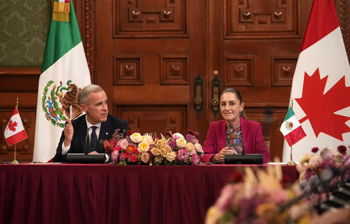 President Sheinbaum and Canada PM Mark Carney sit at a table in the National Palace with Canadian and Mexican flags