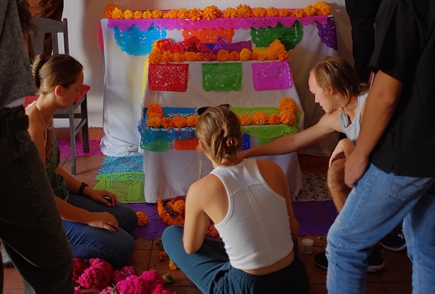 A group of tourists at a colorful day of the dead ofrenda in oaxaca