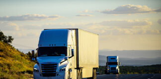 Two trucks or semi-trailers drive down a highway, possibly carrying Mexican exports to the US