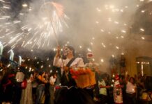 Participants of Oaxaca's Day of the Dead parade with fireworks in the background