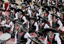 What’s on in November in Mexico City? A large marching band performs in a Día de los Muertos parade in Mexico City, dressed in black mariachi-style outfits with sombreros and their faces painted as calaveras, or skulls.
