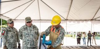 Soldiers destroying confiscated firearms with a machine