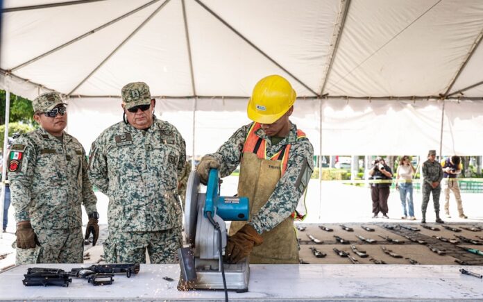 Soldiers destroying confiscated firearms with a machine