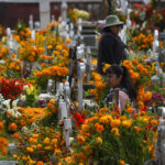 Women in a graveyard filled with orange marigolds