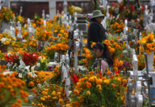 Women in a graveyard filled with orange marigolds