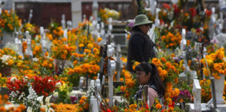 Women in a graveyard filled with orange marigolds