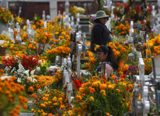 Women in a graveyard filled with orange marigolds