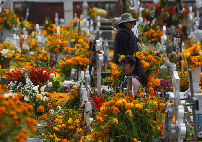 Women in a graveyard filled with orange marigolds
