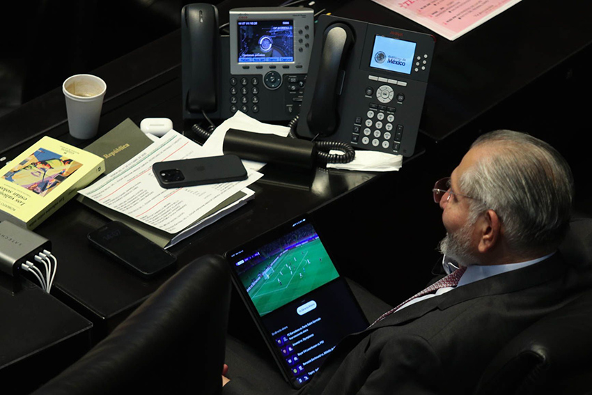 Senator Adán Augusto López watches a soccer game on a tablet during a Senate session