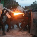 protster aiming fire at police