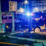Police cars with lights flashing surround a damaged car crashed into a pole at night in Culiacán, Sinaloa