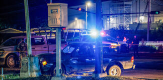 Police cars with lights flashing surround a damaged car crashed into a pole at night in Culiacán, Sinaloa
