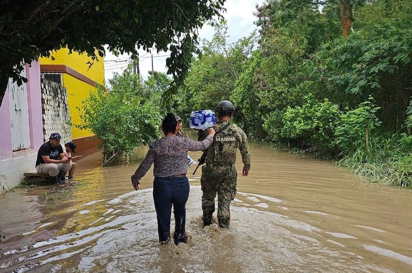 A woman walks with a member of the Navy through knee-high water after major rainfall in central Mexico