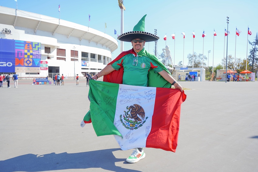 A Mexico soccer fan in a shirt, hat and flag