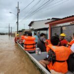 people ride a boat through flooding in Puerto Vallarta