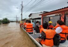 people ride a boat through flooding in Puerto Vallarta