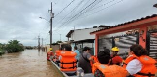 people ride a boat through flooding in Puerto Vallarta