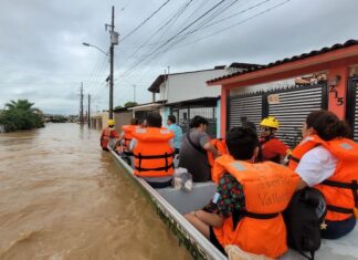 people ride a boat through flooding in Puerto Vallarta