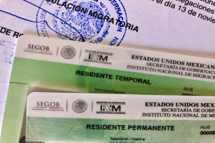 A close-up of two Mexican residency cards: a 'Residente Temporal' (Temporary Resident) card and a 'Residente Permanente' (Permanent Resident) card, on top of official INM immigration paperwork.