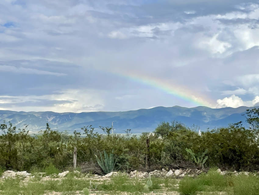 A rainbow arcs over the mountains and desert flora, including agave and cactus, in the sacred land of Wirikuta in San Luis Potosí, Mexico.