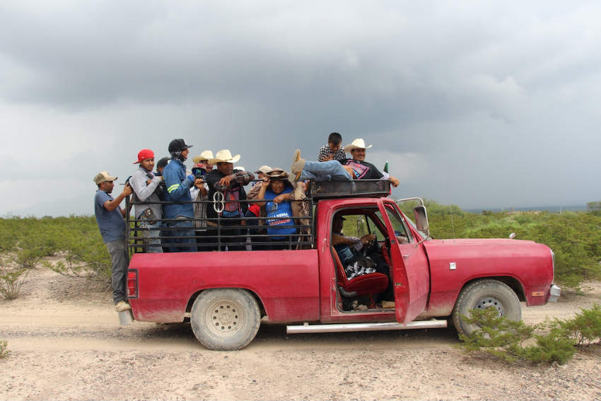Ejido members and supporters riding in the back of a red pickup truck, traveling down a dirt roads around Las Margaritas, San Luis Potosi, Mexico.
