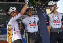 Teammates in cycling gear and helmets places a palm crown on Mexican cyclist Isaac del Toro
