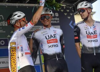 Teammates in cycling gear and helmets places a palm crown on Mexican cyclist Isaac del Toro
