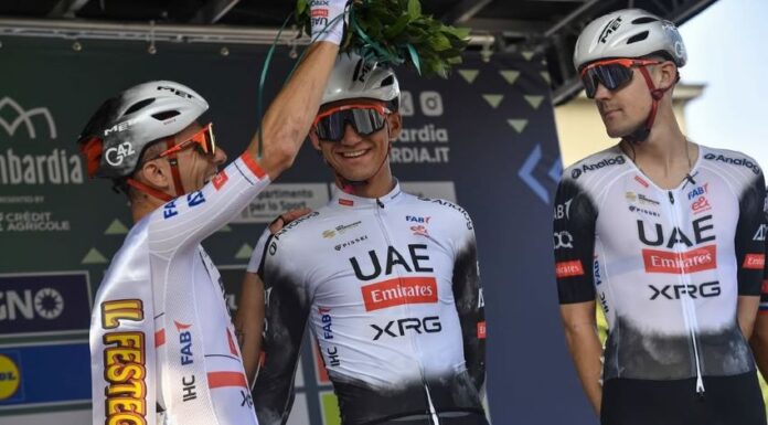 Teammates in cycling gear and helmets places a palm crown on Mexican cyclist Isaac del Toro