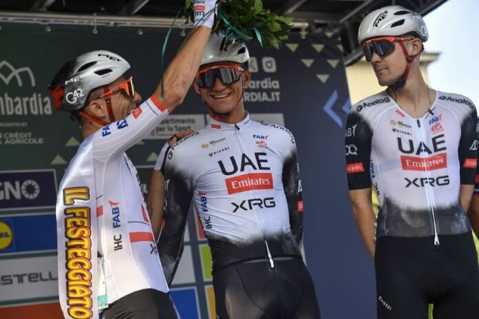 Teammates in cycling gear and helmets places a palm crown on Mexican cyclist Isaac del Toro