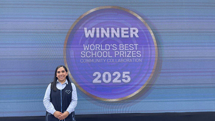 A woman in a Mexican teacher uniform stands in front of a projection reading Winner World's Best School Prizes 2025