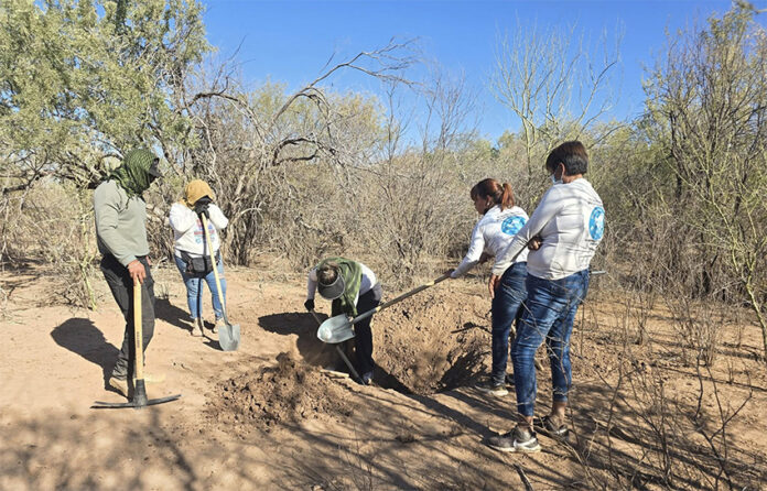 A group of women and a man from Buscadoras Por La Paz in Hermosillo dig a whole in the desert