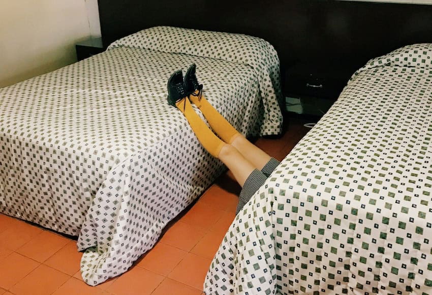 A man sleeping on the floor of a motel room