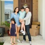 Hispanic mom and dad with their beautiful kids looking happy and smiling together in their beautiful new house entryway