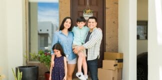 Hispanic mom and dad with their beautiful kids looking happy and smiling together in their beautiful new house entryway
