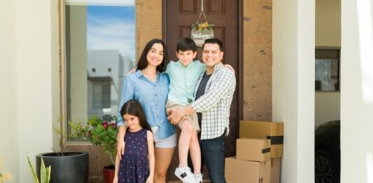 Hispanic mom and dad with their beautiful kids looking happy and smiling together in their beautiful new house entryway
