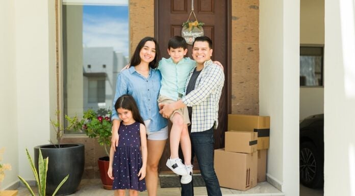 Hispanic mom and dad with their beautiful kids looking happy and smiling together in their beautiful new house entryway
