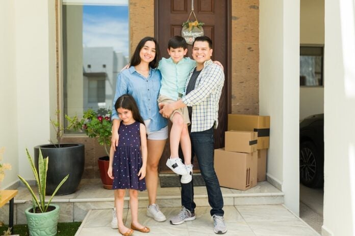 Hispanic mom and dad with their beautiful kids looking happy and smiling together in their beautiful new house entryway