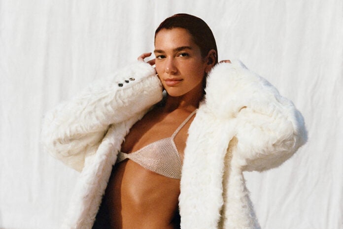 Dua lipa in a white fuzzy coat and shiny bikini top