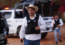 Uruapan Mayor Carlos Manzo in front of a police car wearing a cowboy hat and bullet proof vest