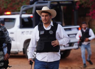Uruapan Mayor Carlos Manzo in front of a police car wearing a cowboy hat and bullet proof vest