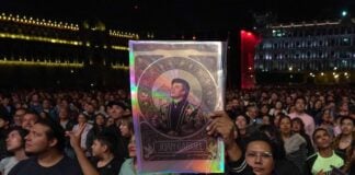 A fan holds up a poster of aJuanga at the 1990 Bellas Artes concert screening in Mexico City's Zócalo