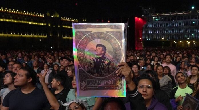 A fan holds up a poster of aJuanga at the 1990 Bellas Artes concert screening in Mexico City's Zócalo