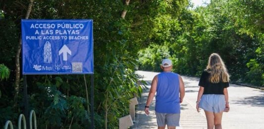 two people walking towards a beach in Tulum
