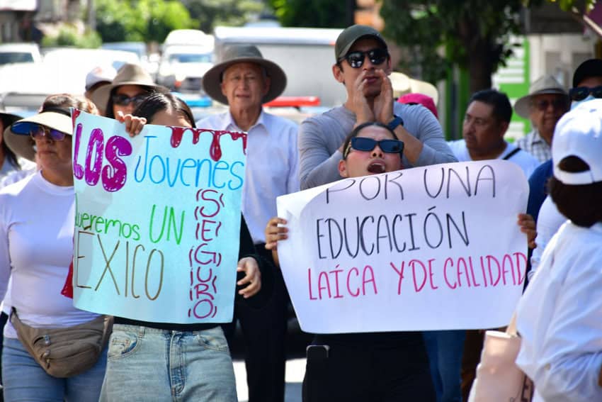 Demonstrators in Chilpancingo, Mexico, hold signs reading "Young people want a safe Mexico" and "For a secular and quality education" during a political protest