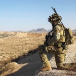 A US soldier in camo surveils a desert valley in New Mexico